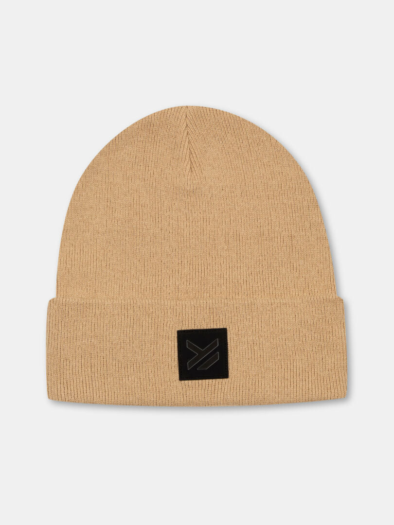 The Vataja Beanie by Halti is a beige recycled polyester knit with a folded brim and sleek black patch—perfect for winter.