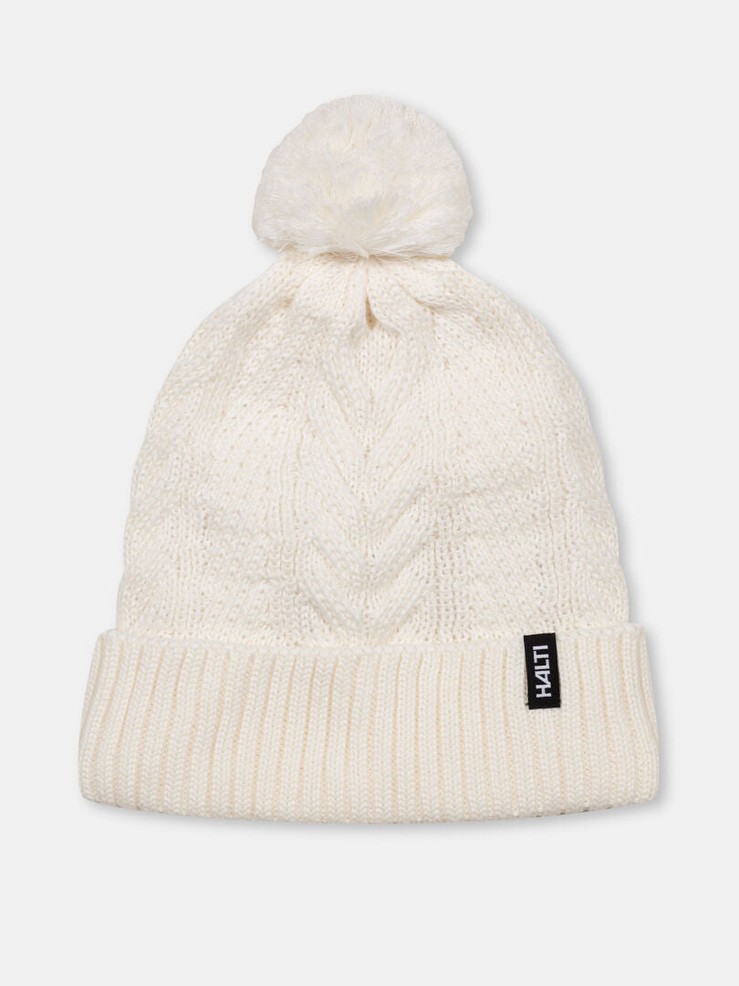 Halti Hile Beanie: white cable knit, folded brim, pom-pom, black tag—your ideal winter hat.