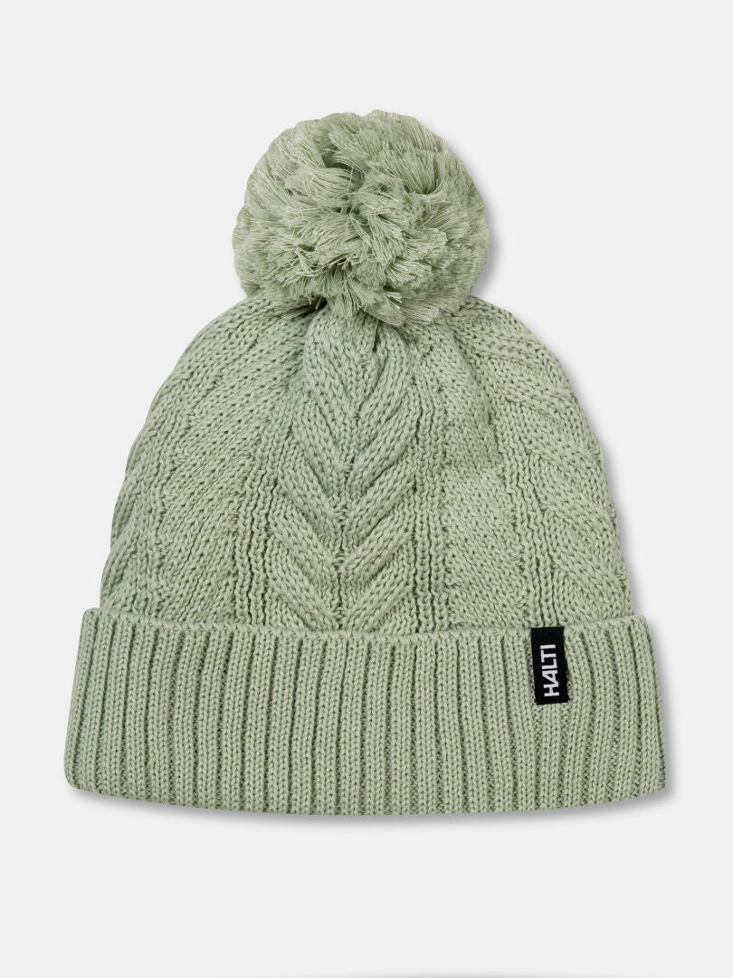 Halti Hile Beanie: light green, fleece-lined with pom-pom, ribbed cuff & black tag—ideal winter hat.