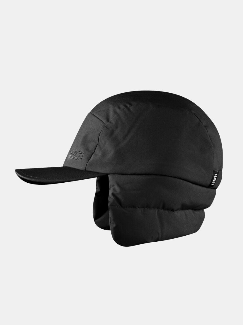 Halti Huove Puffy Hat: black, insulated, flat brim, padded ear flaps—shown on a plain light gray background.