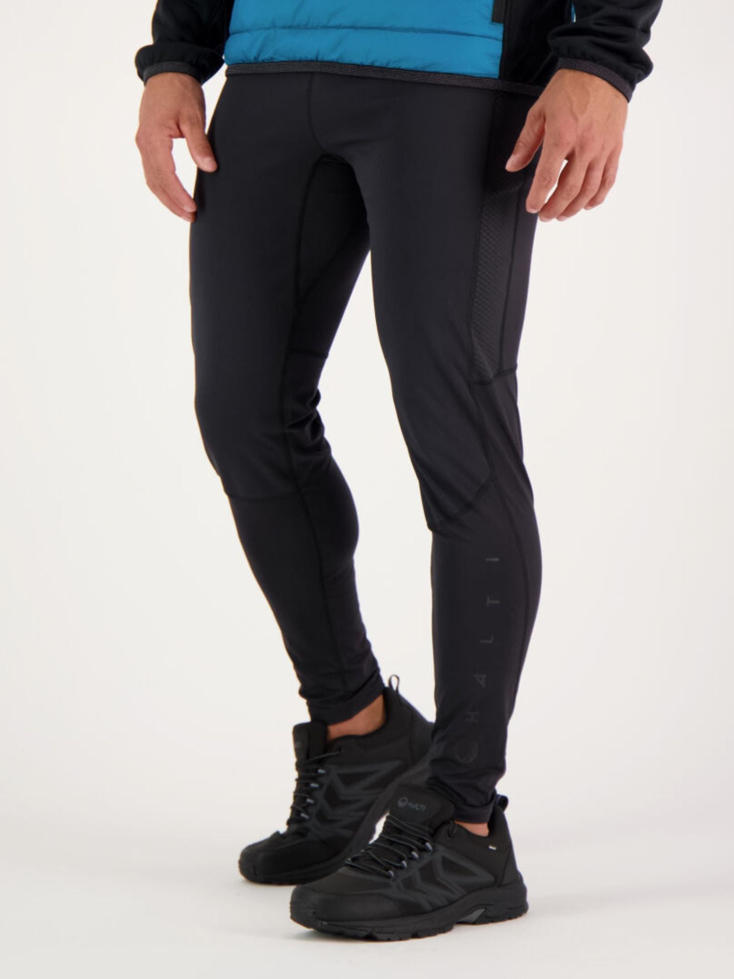 Wearing Halti Suunta Men's Hybrid Tights, black running shoes, and a blue jacket, ready for outdoor training.