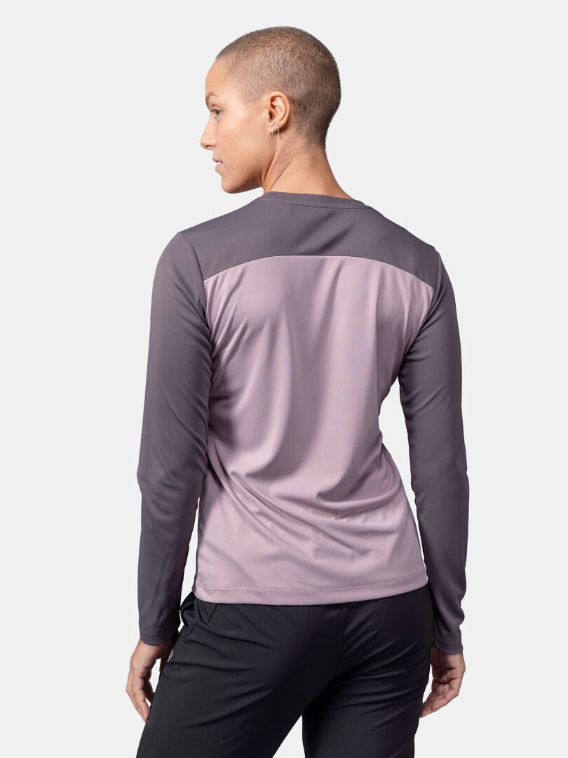 Woman with short hair wears Halti Salves Training Shirt and black pants, facing away from the camera.