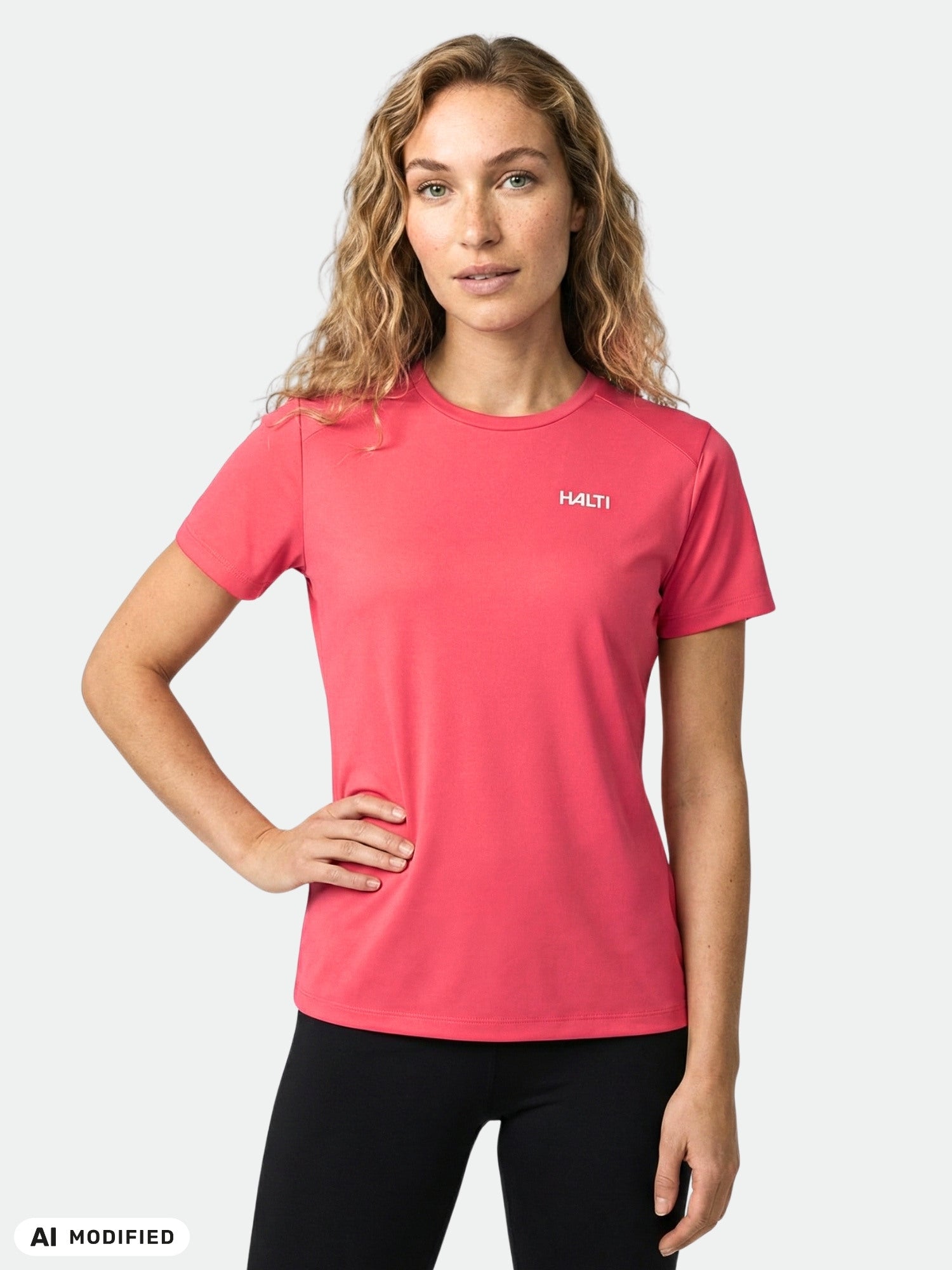 Woman wears Halti Salves T-shirt in pink with black pants, posing with one hand on her hip against a plain backdrop.