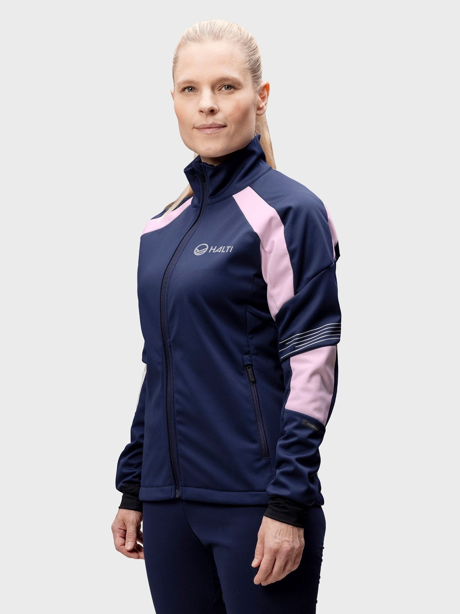 A woman wears the Halti Hyyde XC Set in navy and pink, standing against a plain light background.