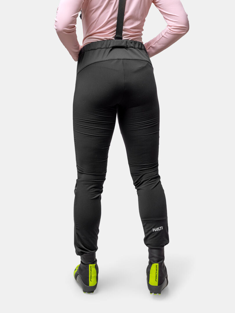 A person in Halti's Huuru XC Set Women's and neon green cycling shoes, ready for winter training, seen from behind.