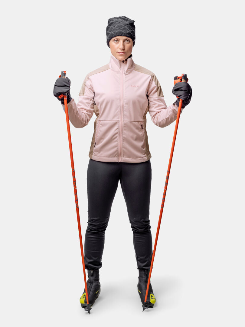 A woman in the Halti Huuru XC Set stands with ski poles and skis, ready for cross-country skiing.