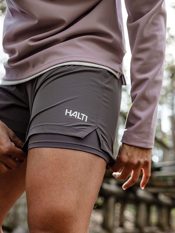 Woman outdoors adjusting her Halti Uurto Shorts Women's, paired with a long-sleeve shirt.