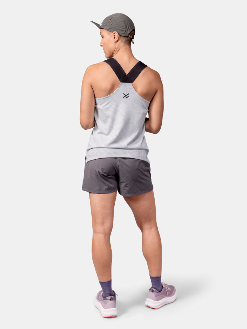 Back view of a person in Halti Oulanka Training Top Women's, grey shorts, khaki cap, and lavender trail shoes.