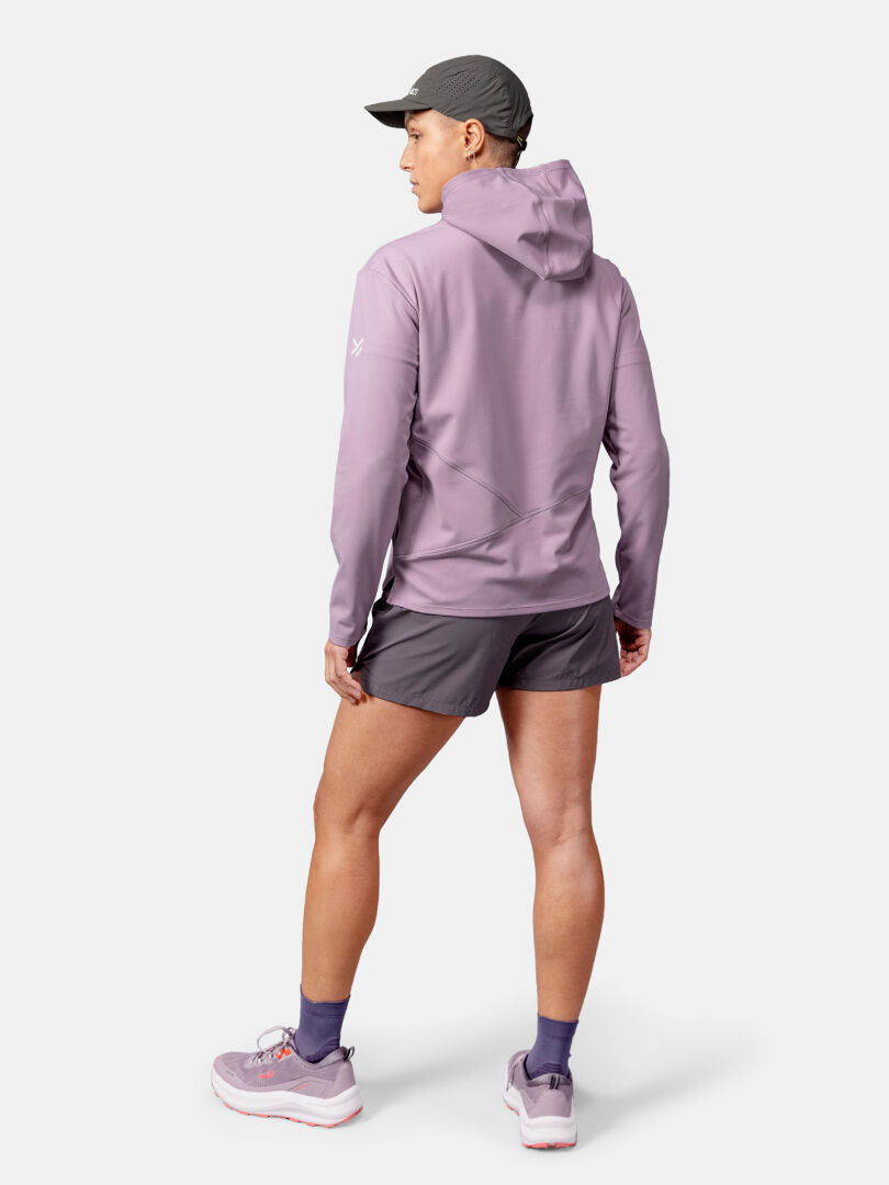 A person wearing the Halti Kaltio Training Hoodie Women's, gray shorts, cap, and sneakers stands facing away.