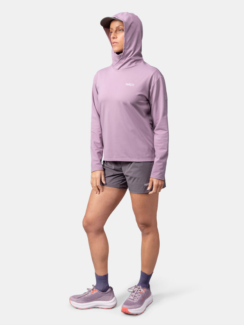 A person wears the Halti Kaltio Training Hoodie Women's, gray shorts, and athletic shoes against a white background.