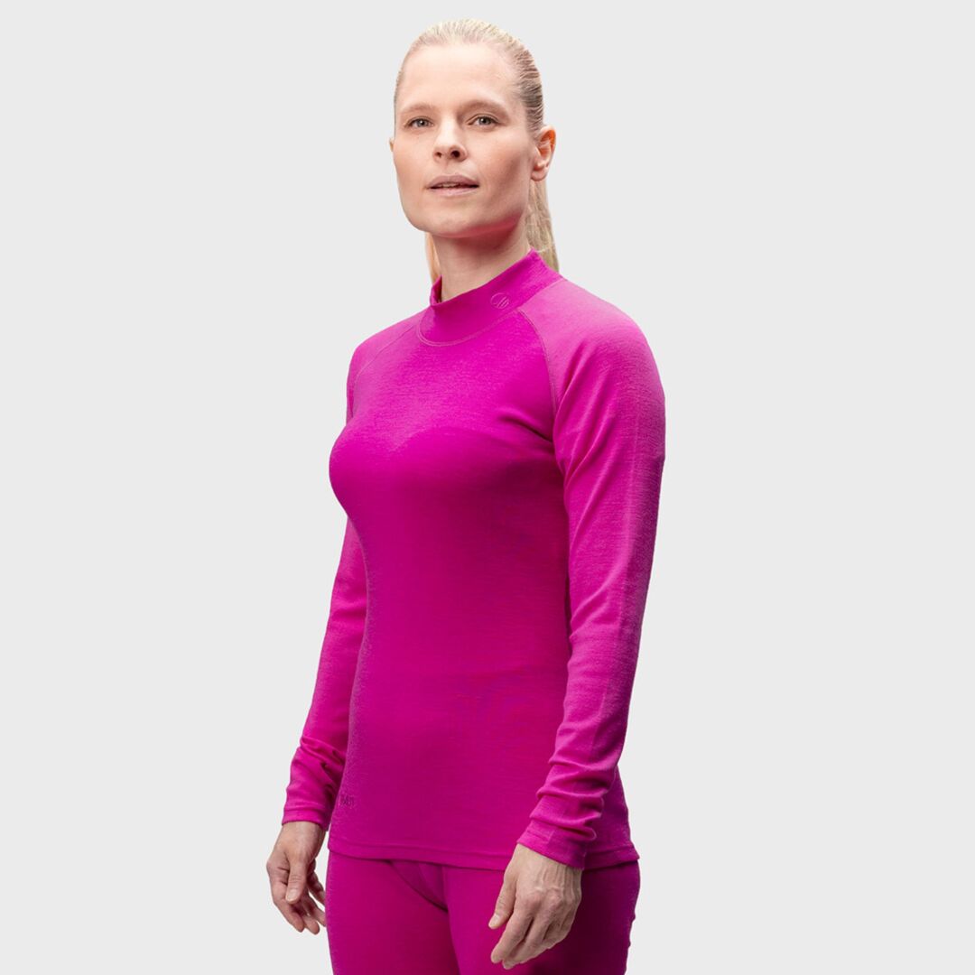 A woman wears the Halti Neva Merino Base Layer Set in vibrant pink, shown against a plain light gray background.