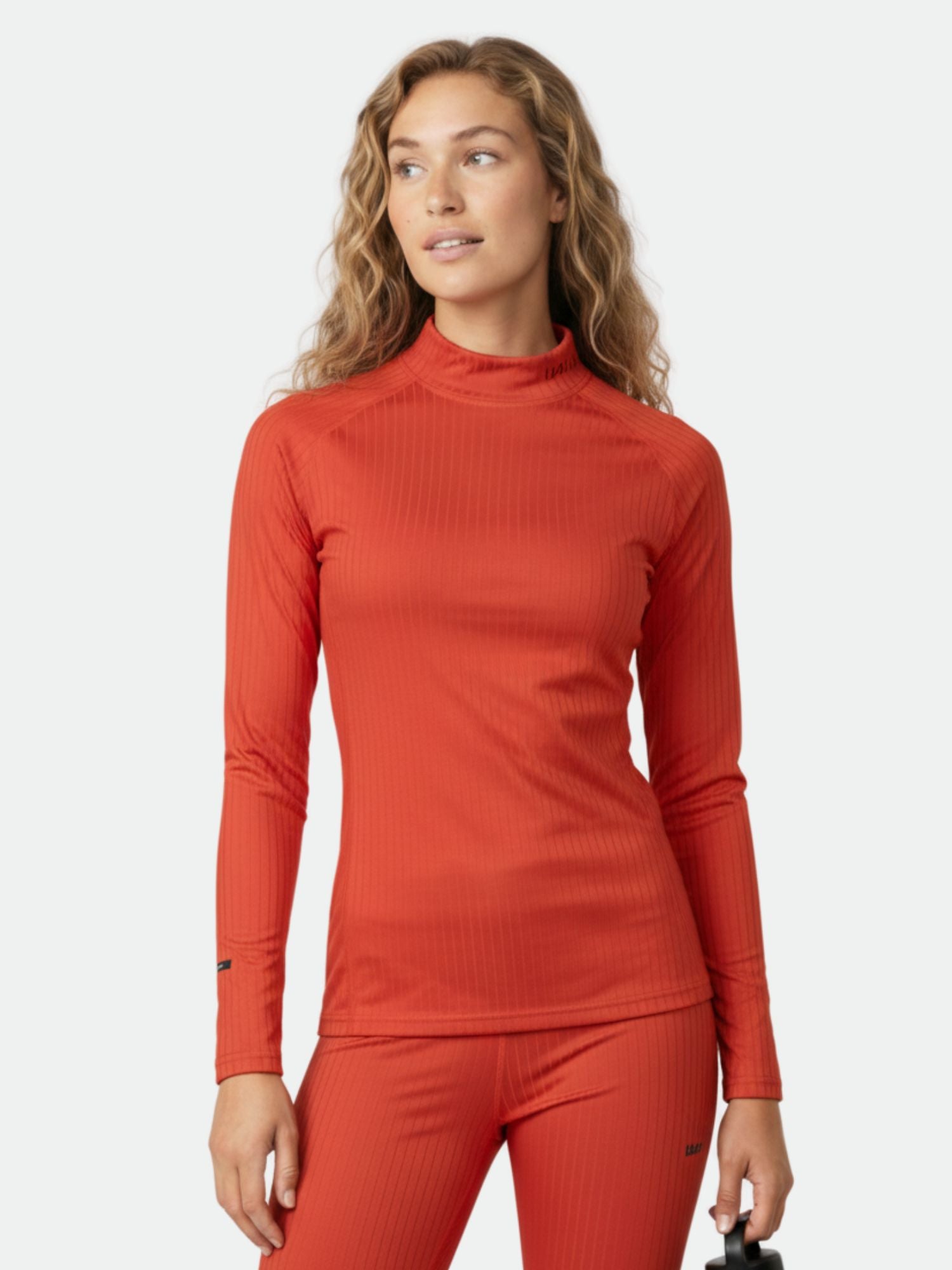 Woman wearing Halti Dual Base Layer Set, a fitted orange recycled polyester outfit ideal for outdoor adventures.