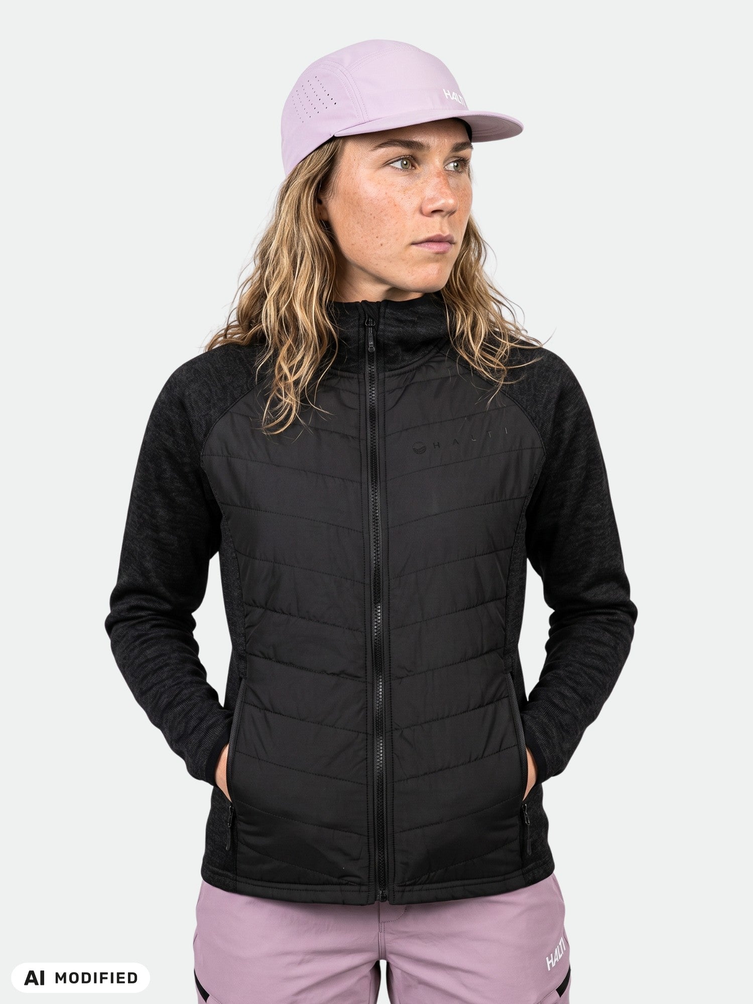Woman in Halti Streams Hybrid Layer Jacket, light purple cap and pants, standing against a plain light background.