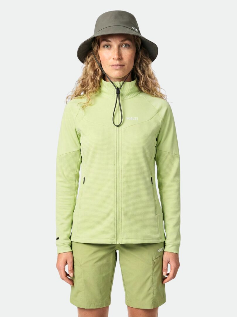 A person in the Halti HeatGrid Layer Jacket Women's, matching shorts, and an olive bucket hat stands against a plain background.