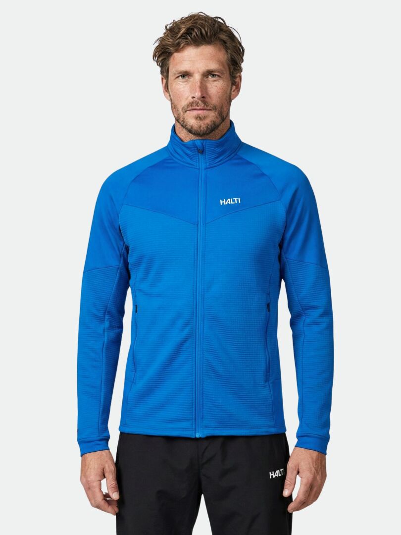 A man wears the Halti HeatGrid Layer Jacket Men's in bright blue with black pants, standing against a white background.