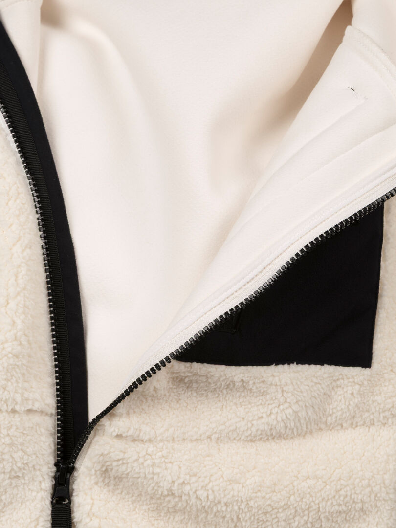 Close-up of Halti Lumista Polar Fleece Jacket Women’s, windproof cream fabric with a black inner pocket, partially unzipped.