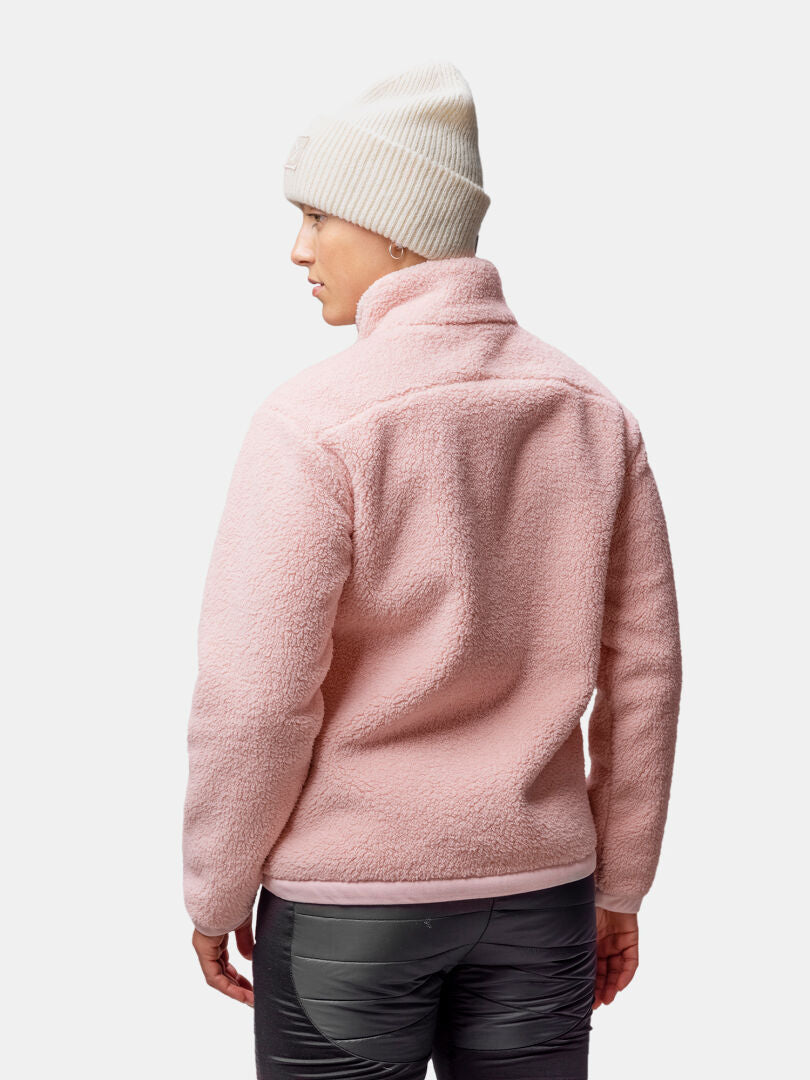Woman in Halti Lumista Polar Fleece Jacket, pink, white knit beanie, gray pants, back view on plain background.