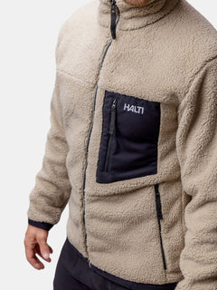 A man wears the Halti Lumista Polar Fleece Jacket in beige, featuring a black zippered chest pocket.