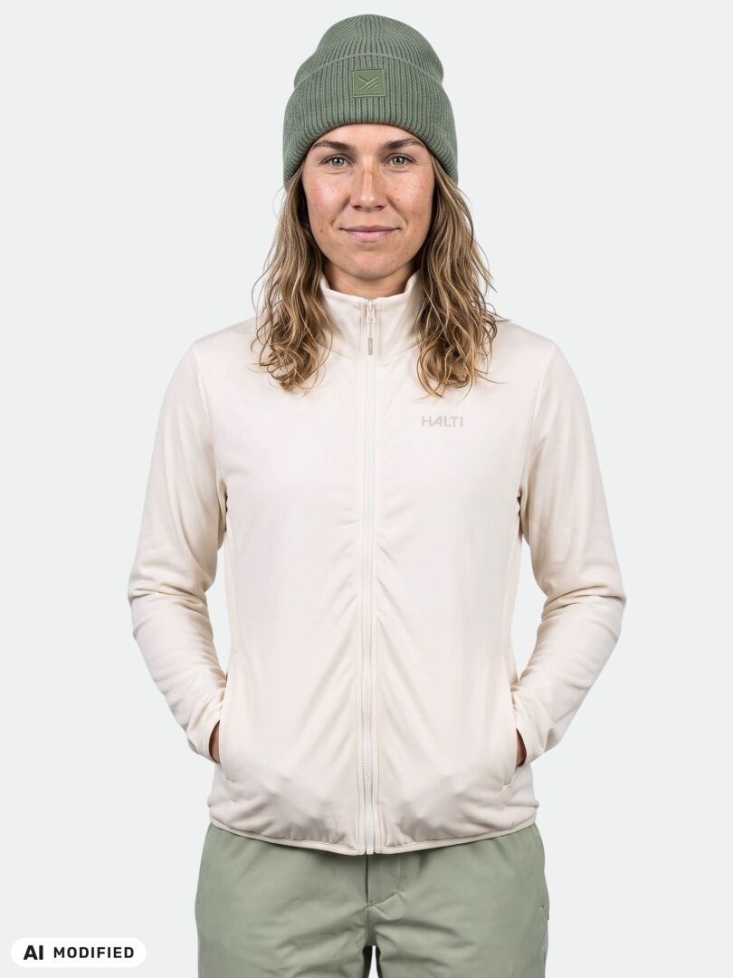 A woman in an olive beanie wears a white Halti Rockmoon Fleece Jacket, posing against a white background.