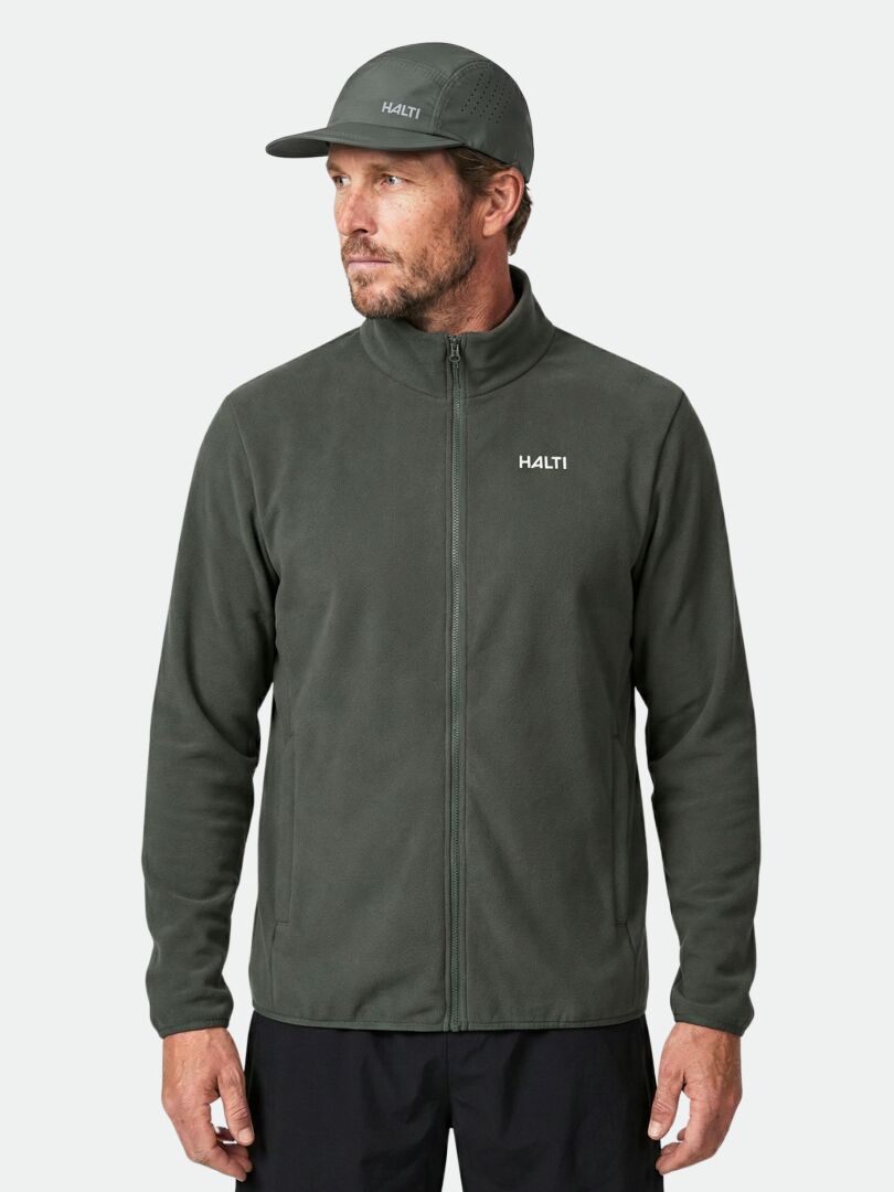 A man wears a dark green Halti Rockmoon Fleece Jacket and matching cap, standing against a plain background.