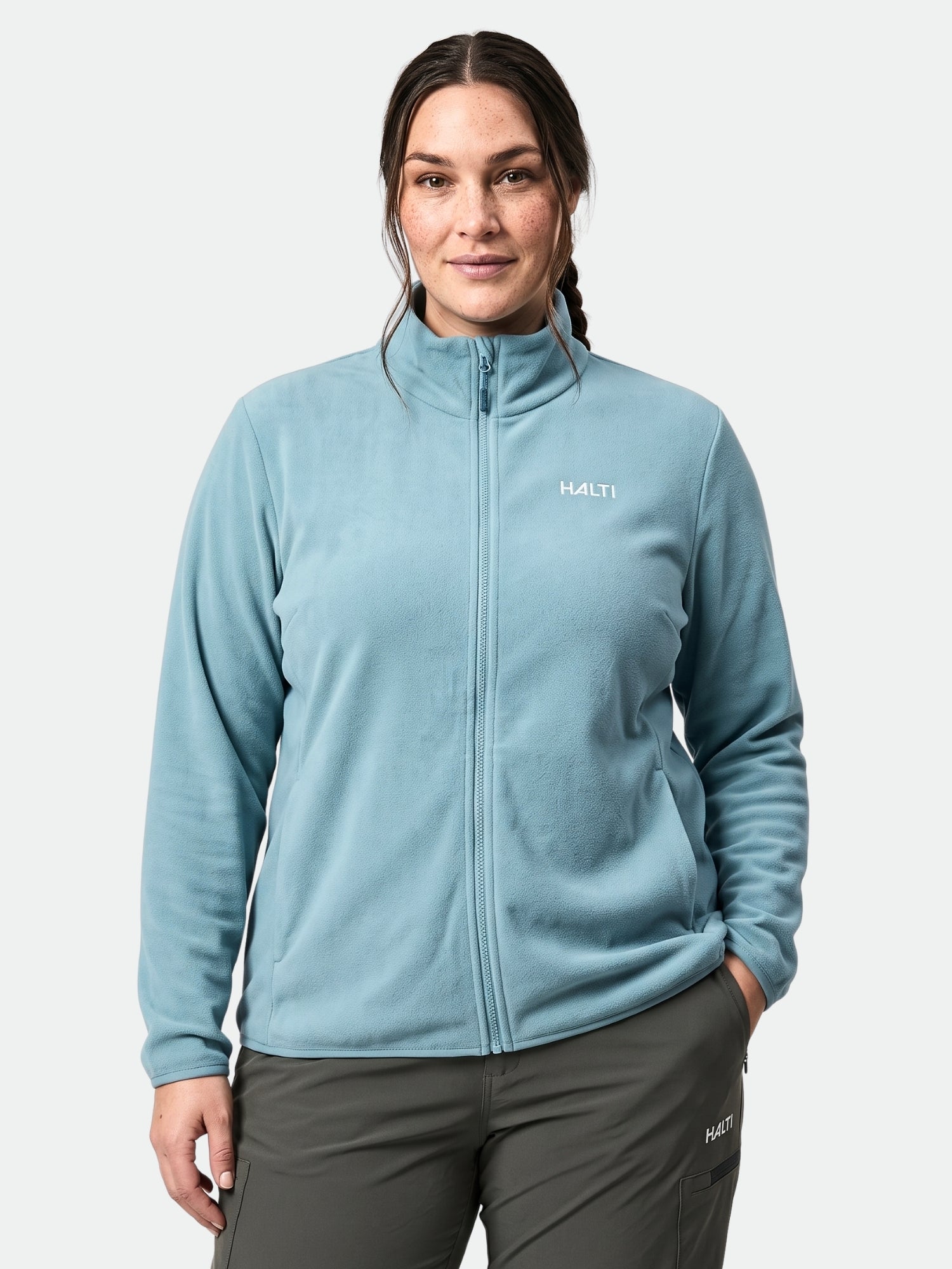 A woman wears the Halti Rockmoon Fleece Jacket Women's Plus in light blue with dark pants, against a plain background.
