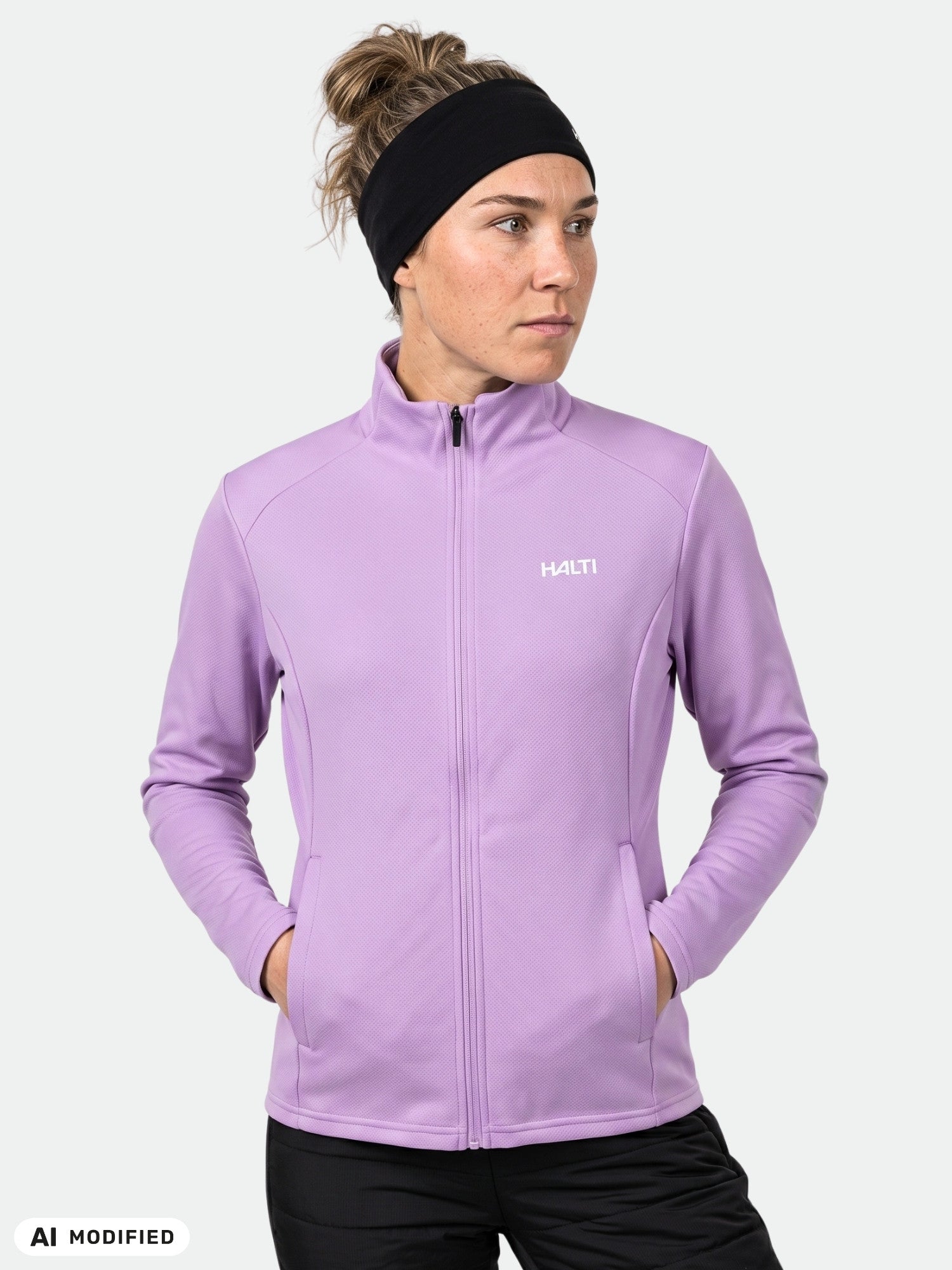 A woman in a Halti Kivikko Layer Jacket stands with hands in pockets, wearing a black headband.