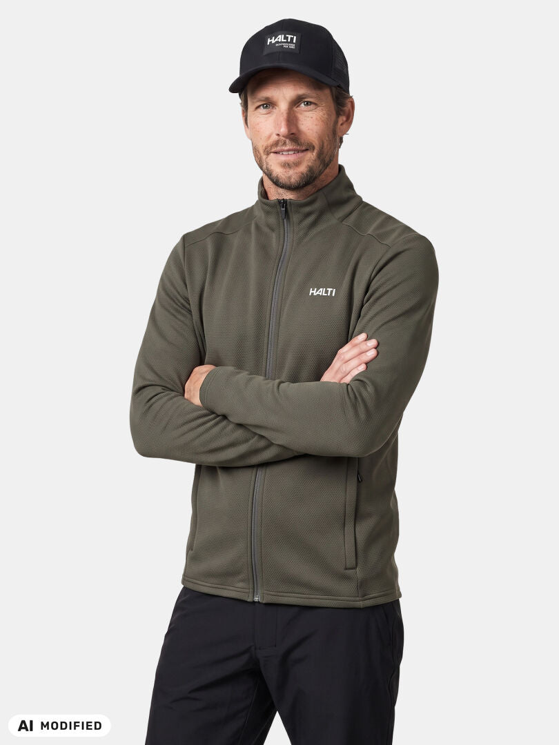 Man in Halti Kivikko Layer Jacket and black cap stands with arms crossed, ready for outdoor training.