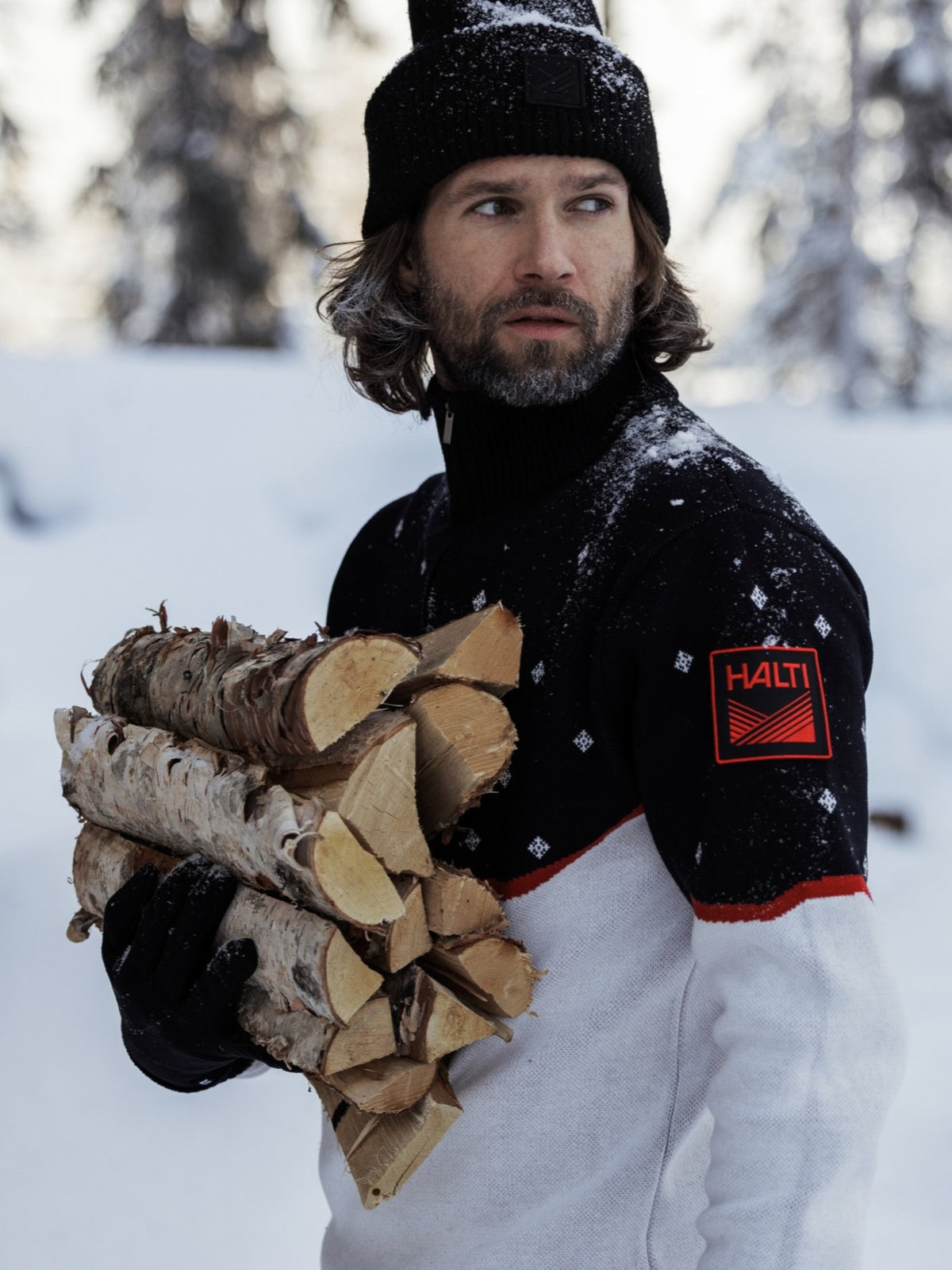 A man in a patterned sweater and knit hat carries firewood in a snowy forest, featured on a Halti Global Store Gift Card.