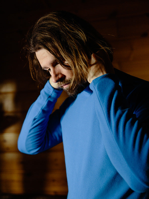 Man wearing a blue sweater against a wooden background